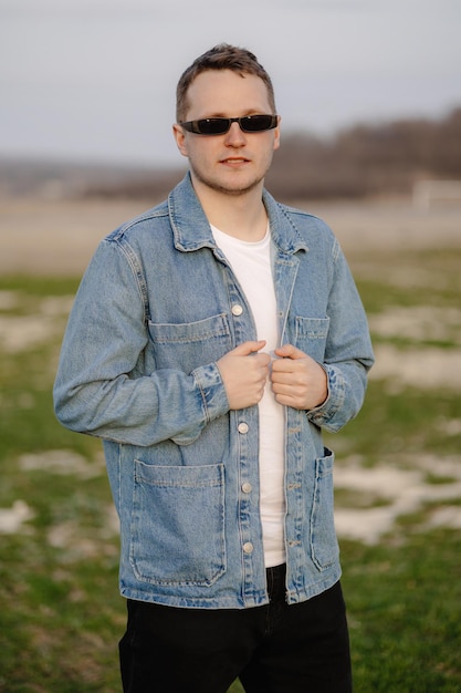 Ein Mann in einer blauen Jeansjacke steht auf einem Feld