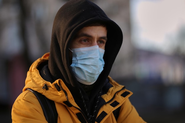 Ein Mann in einer medizinischen Maske auf der Straße Der Typ in der medizinischen Maske auf dem Hof