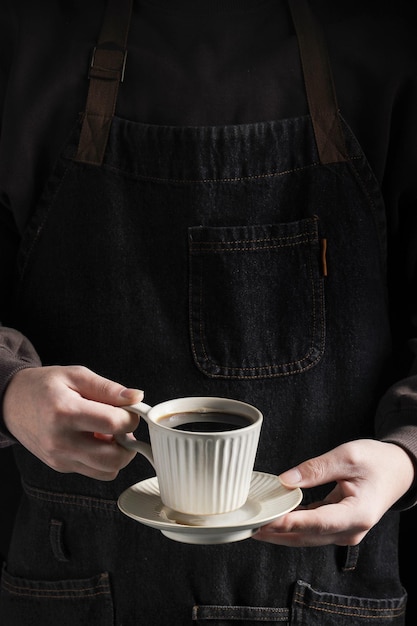 Ein Mann in einer Schürze hält eine Tasse Kaffee in der Hand. Entspannung bei Kaffee