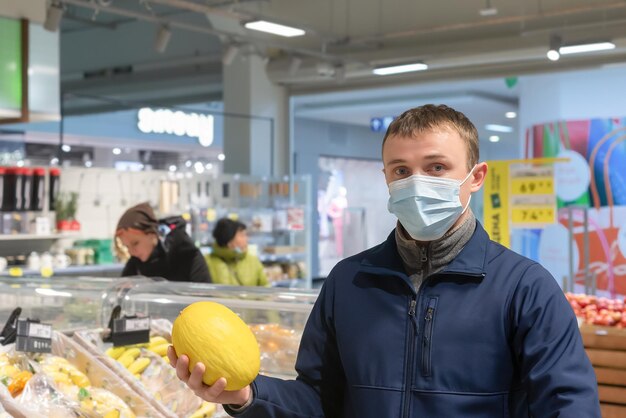 Ein Mann in einer schützenden Gesichtsmaske mit einer Melone in der Hand Quarantine Lifestyle Food und Drinks