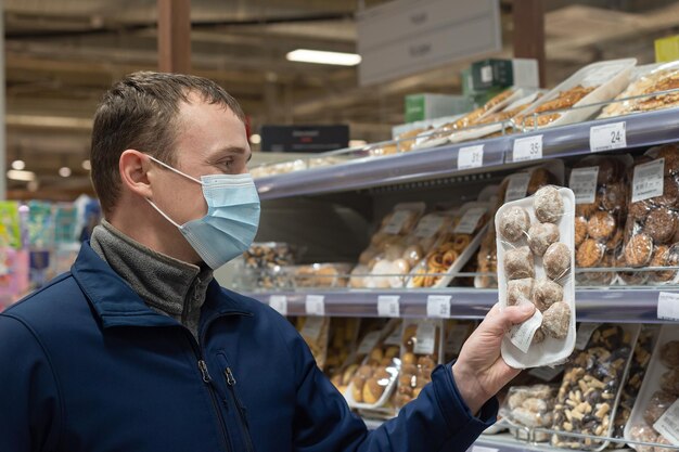 Ein Mann in einer schützenden Gesichtsmaske wählt Lebensmittel im Laden aus Lifestyle und Sicherheit Einzelhandel