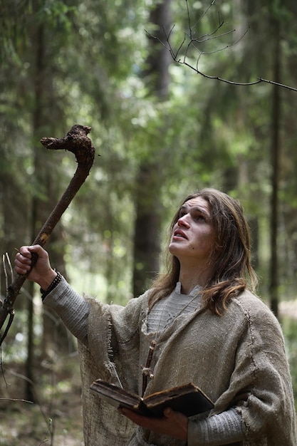 Ein Mann in einer Soutane verbringt ein Ritual in einem dunklen Wald