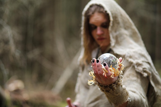 Ein Mann in einer Soutane verbringt ein Ritual in einem dunklen Wald