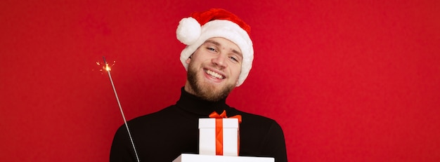 Ein Mann in einer Weihnachtsmannmütze mit Geschenkboxen und einer Wunderkerze