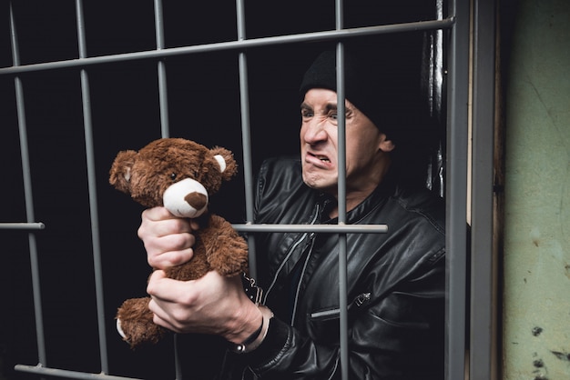 Ein mann in handschellen sitzt hinter gittern in einer polizeistation.