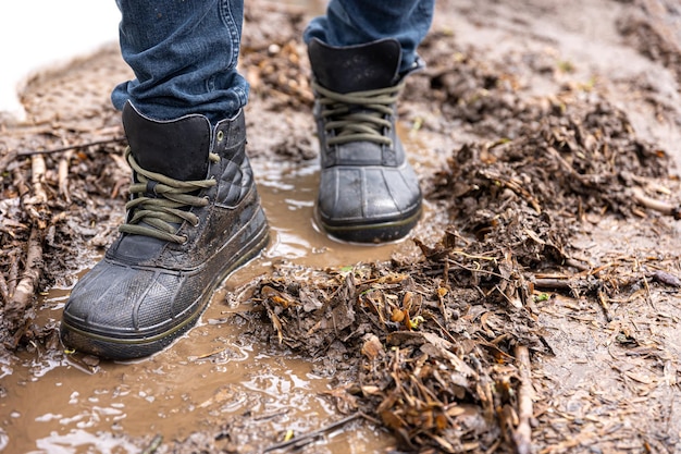 Ein Mann in Jeans und Stiefeln geht bei Regenwetter durch den Sumpf