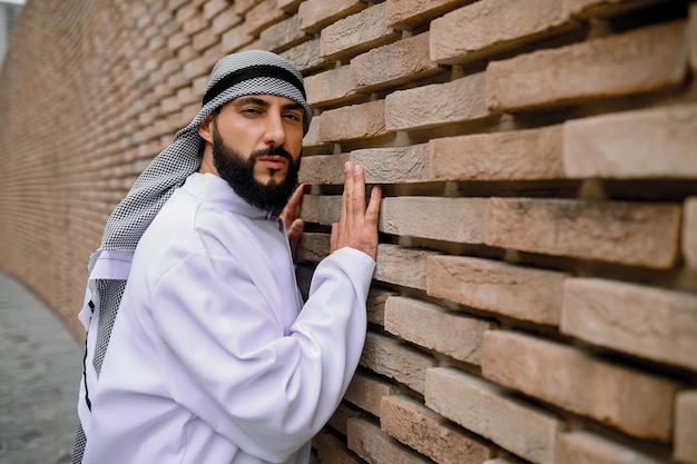 Ein Mann in traditioneller arabischer Kopfbedeckung, der in der Nähe der Mauer steht