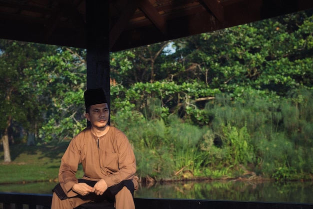 Foto ein mann in traditioneller kleidung sitzt gegen pflanzen