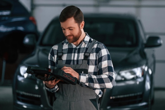 Ein Mann in Uniform hält ein Tablet und arbeitet im Autosalon