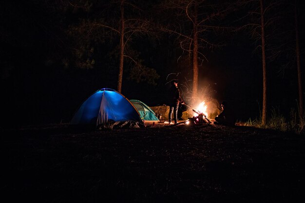 Foto ein mann in voller länge, der nachts am lagerfeuer steht