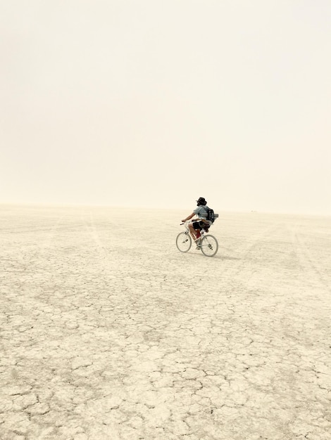 Ein Mann in voller Länge fährt in der Wüste mit dem Fahrrad