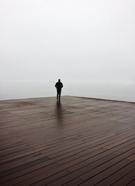 Foto ein mann in voller länge steht auf einem pier vor klarem himmel