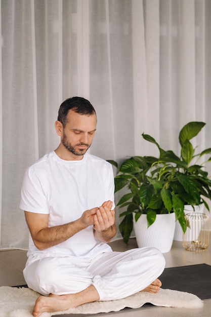 Ein Mann in weißer Sportbekleidung macht Yoga mit einem Fitnessraum das Konzept eines gesunden Lebensstils