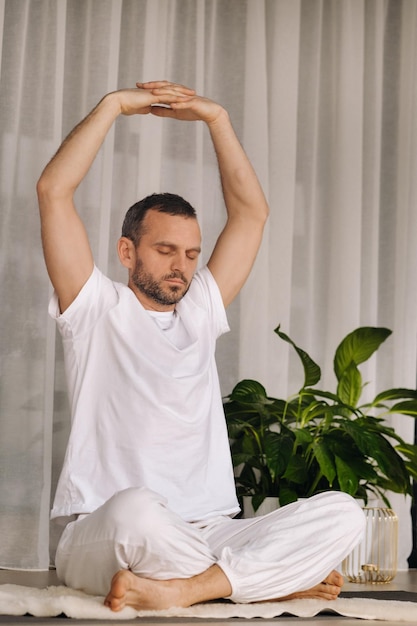 Ein Mann in weißer Sportbekleidung macht Yoga mit einem Fitnessraum das Konzept eines gesunden Lebensstils
