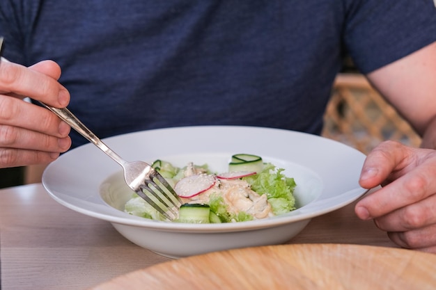 Ein Mann isst in einem Café einen Salat mit Tintenfischgurken und Gemüse mit Austernsauce