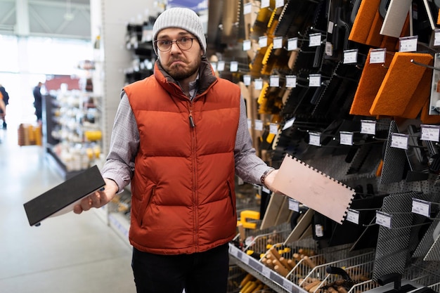 Ein Mann kann den Unterschied zwischen zwei Wandputzwerkzeugen in einem Baumarkt nicht herausfinden