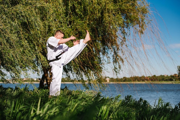 Ein Mann Karate-Kämpfer im weißen Kimono-Training im Freien im Park