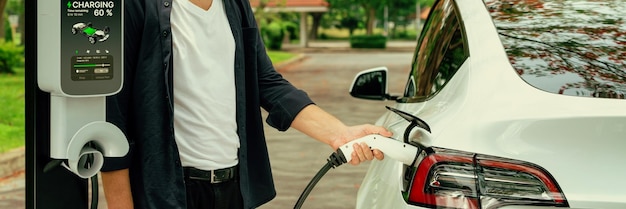 Ein Mann laden im Herbst die Batterie für ein Elektroauto auf Exalt