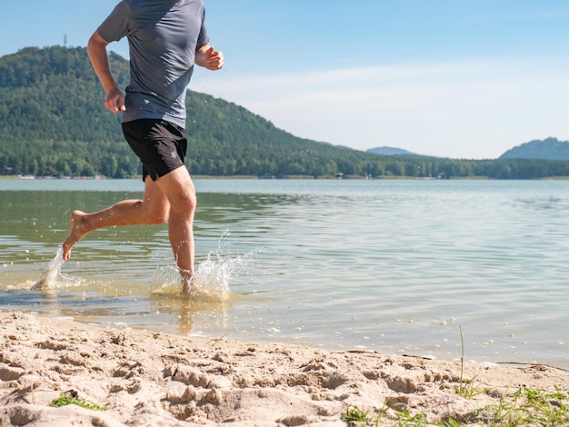 Ein Mann läuft im See und spritzt Wasser um ihn herum, läuft im Meer, ein glücklicher Mann, seine Füße spritzen Wasser.