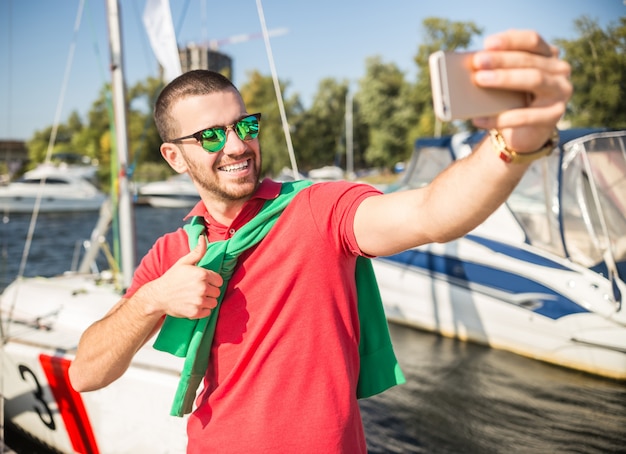 Ein Mann macht ein Foto vor der Yacht und lächelt.