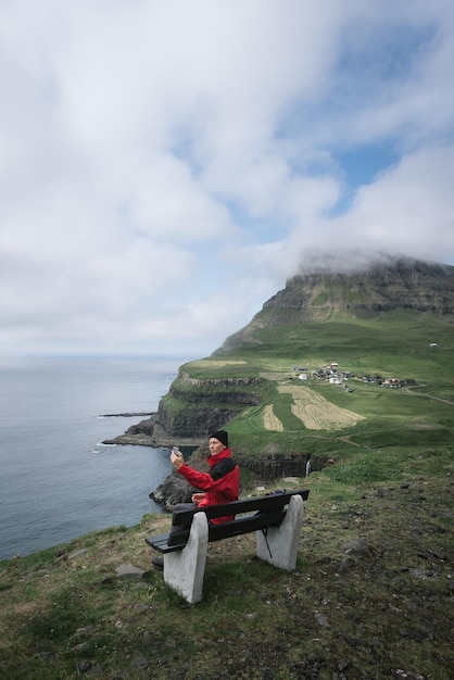 Foto ein mann macht ein selfie vor dem dorf gasadalur auf den färöerinseln