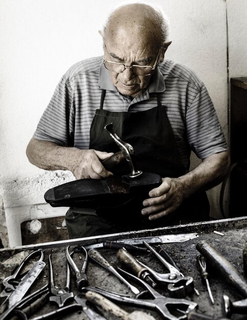 Foto ein mann macht einen schuh, während er in einer werkstatt sitzt