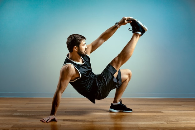 Ein Mann macht funktionelle Übungen im Fitnessstudio auf grauem Hintergrund