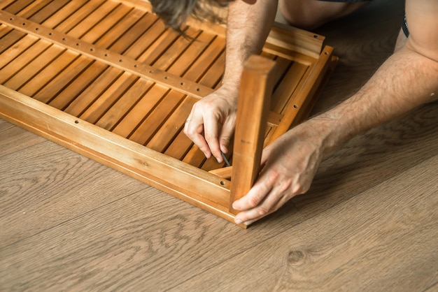 Ein Mann macht Holz Ein Meister mit Werkzeugen repariert Möbel Reparatur von Möbeln Vater sammelt Möbel zu Hause Restaurierung von Hausmöbeln