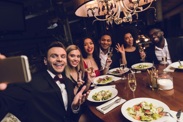 Ein Mann macht Selfies mit Freunden im Restaurant.