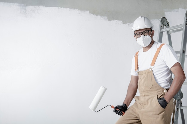 Ein Mann malt mit einer Rolle eine weiße Wand. Reparatur des Innenraums.