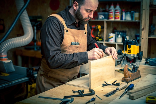 Foto ein mann markiert holz in einer werkstatt.