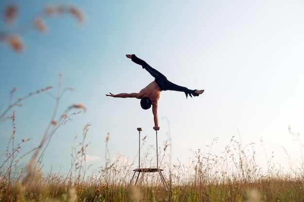 Ein Mann mit athletischem Körperbau führt komplexe Gymnastikübungen auf einem Feld durch