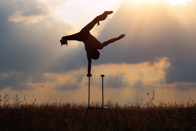 Ein Mann mit athletischem Körperbau führt komplexe Gymnastikübungen auf einem Feld durch