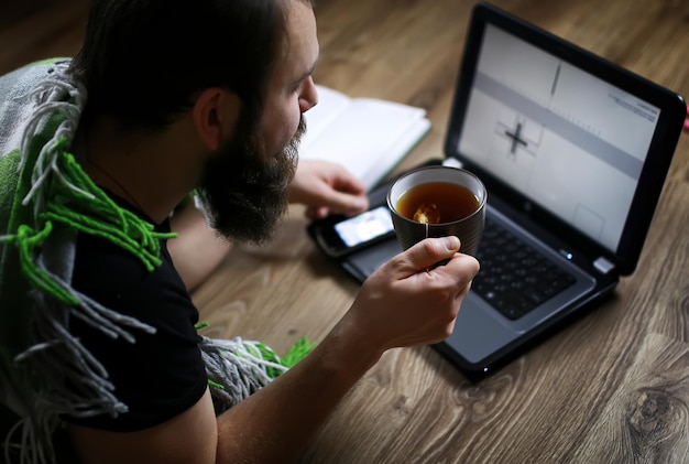 Foto ein mann mit bart arbeitet an einem computer, der auf dem boden liegt