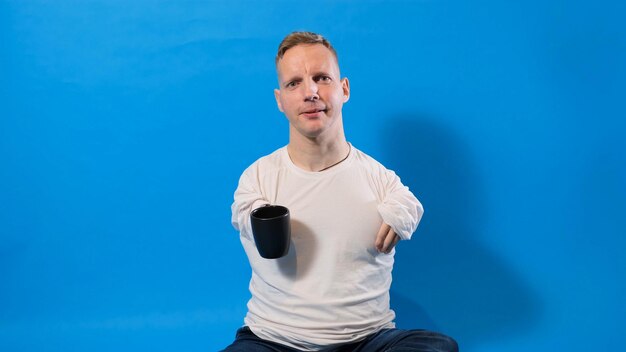 Ein Mann mit Behinderungen trinkt Tee aus einer Tasse auf blauem, isoliertem Hintergrund