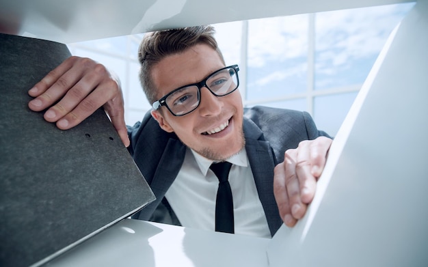 Ein Mann mit Brille schaut sich im Büro einen Ordner mit Dokumenten an