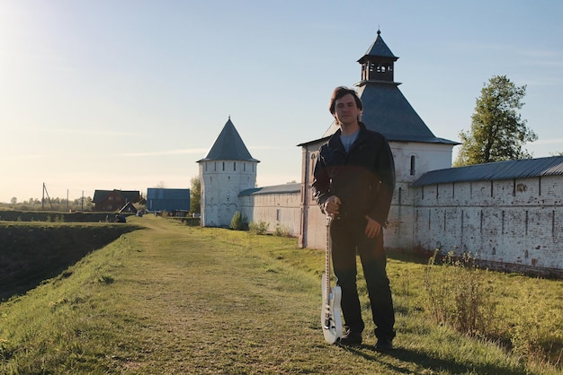 Ein Mann mit E-Gitarre in der Industrielandschaft im Freien