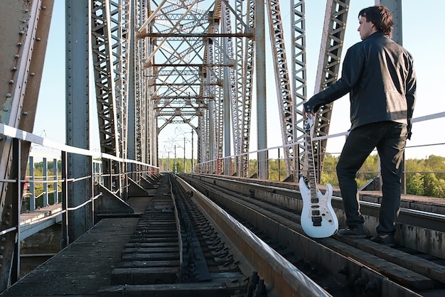 Ein Mann mit E-Gitarre in der Industrielandschaft im Freien