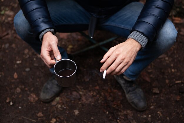 Ein Mann mit einem Glas und einer Zigarette im Wald