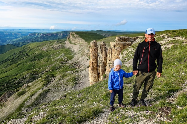 Ein Mann mit einem Kind auf dem Hintergrund von zwei Mönchsfelsen in einer Wolke Bermamyt-Plateau Russland 2021 Juni