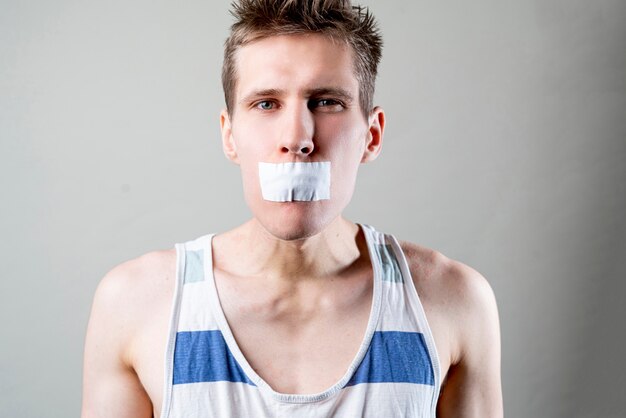 Ein Mann mit einem Klebeband schließt den Mund, hört auf zu reden und schließt sich, Zensurkonzept,