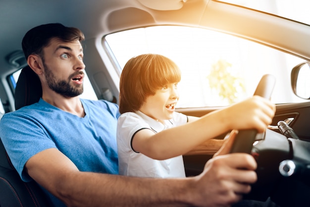 Ein Mann mit einem kleinen Sohn sitzt am Steuer des Autos.