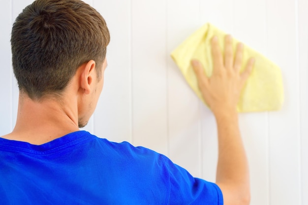 Ein Mann mit einem Lappen in der Hand wäscht die Wand im Zimmer