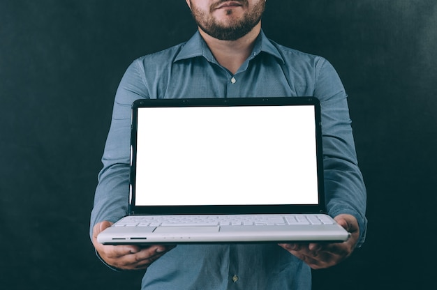 Ein Mann mit einem Laptop in den Händen im Dunkeln