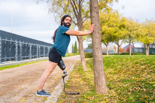 Ein Mann mit einem Prothesenbein streckt sich nach dem Laufen in einem Park aus