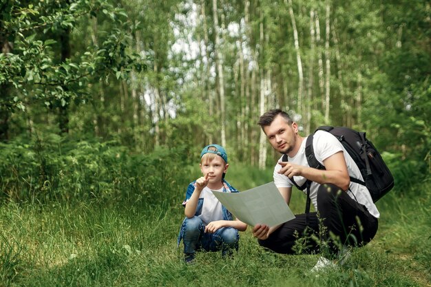 Ein Mann mit einem Rucksack, ein Vater und sein Sohn schauen sich auf einer Wanderung die Karte an und gehen bei Spaziergängen im Wald spazieren.