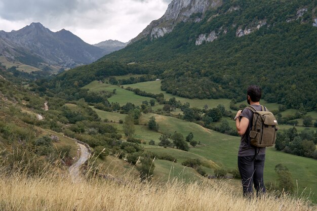 Foto ein mann mit einem rucksack in den bergen. eine sehr lange straße in der ferne.