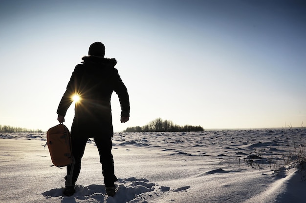 Ein Mann mit einem Rucksack reist im Winter Ein Mann in einem schneebedeckten Feld Wandern Winterlandschaft