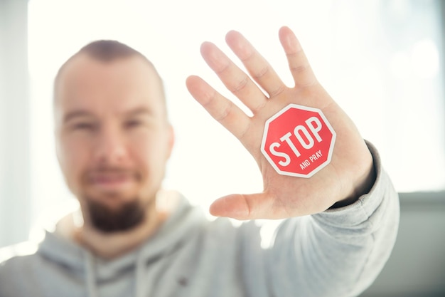 Ein Mann mit einem Stoppschild an der Hand, auf dem „Halt“ steht