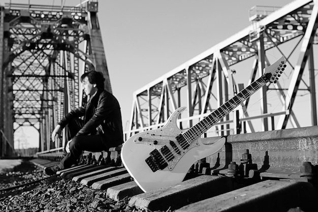 ein Mann mit einer E-Gitarre in der Industrielandschaft im Freien monochrom